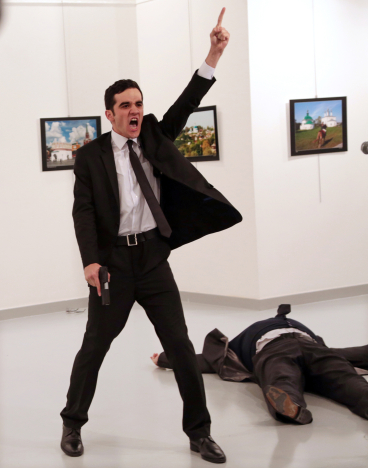 Mevlut Mert Altintas shouts after shooting Andrei Karlov, right, the Russian ambassador to Turkey, at an art gallery in Ankara, Turkey, Monday, Dec. 19, 2016. At first, AP photographer Burhan Ozbilici thought it was a theatrical stunt when a man in a dark suit and tie pulled out a gun during the photography exhibition. The man then opened fire, killing Karlov. (AP Photo/Burhan Ozbilici)